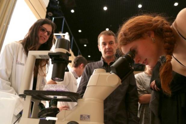 Una noia mira pel microscopi en una demostració científica.